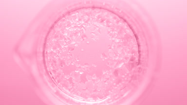 Crystals fall down into clear fluid in flask creating bubbles