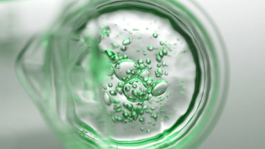 Green liquid pouring into beaker from flask creates bubbles
