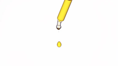 Drop of yellow transparent liquid is falling down from dropper