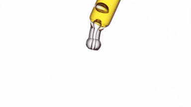 Yellow drop is falling down from lab dropper