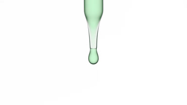 Drop of green transparent fluid is falling down from dropper
