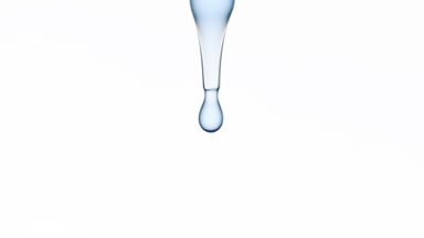Drops of blue clear liquid are falling down from lab dropper