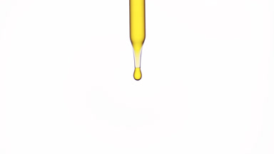 Drops of olive oil are falling down from lab dropper