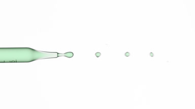 Green fluid flows from graduated lab dropper
