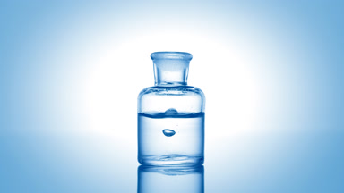 Drop falling into old fashioned bottle with clear liquid