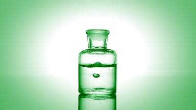 Drop falling into old fashioned bottle with clear liquid