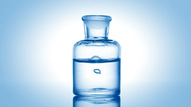 Drop falling into old fashioned bottle with clear fluid
