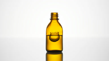 Drop falls into yellow bottle with liquid creating splash