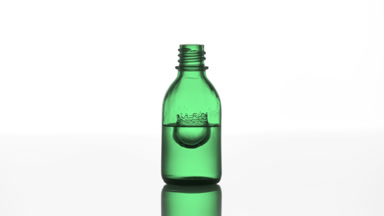 Drop falls into green medical bottle with liquid creating splash
