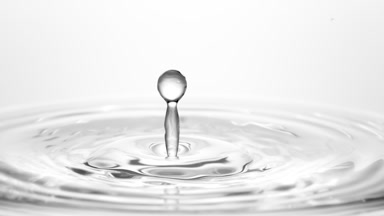 Grey drop falls down on surface of grey liquid creating circles