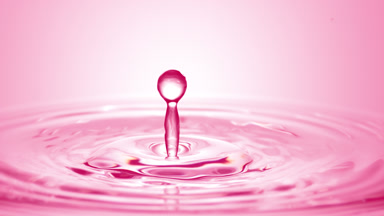 Pink drop falls down on surface of pink liquid creating circles