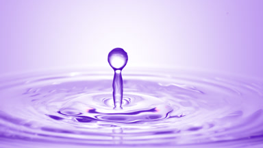 Purple drop falls on surface of purple liquid creating circles
