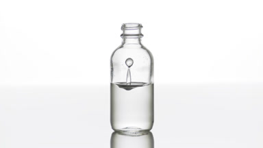 Hyaluronic acid falls down into medical bottle with grey liquid