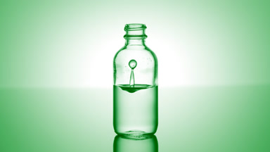 Citric acid falls down into medical bottle with green liquid