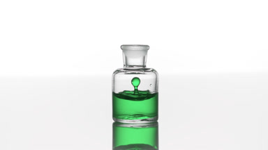 Eucalyptus oil falls down into clear bottle with green liquid