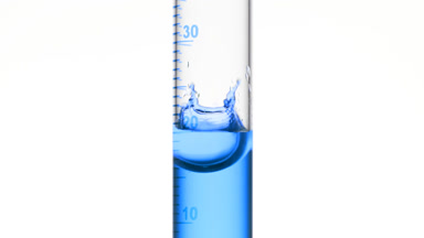 Drop of blue fluid is falling down into graduated cylinder