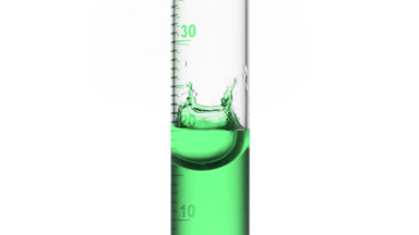 Drop of green fluid is falling down into graduated cylinder