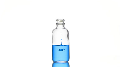 Biotin is falling down into medical bottle with blue liquid