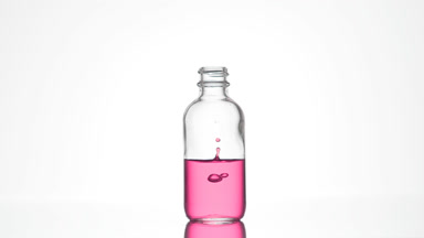 Retinol is falling down into medical bottle with pink liquid