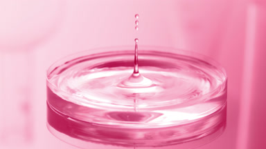 Water drop falls into Petri dish with liquid creating ripples