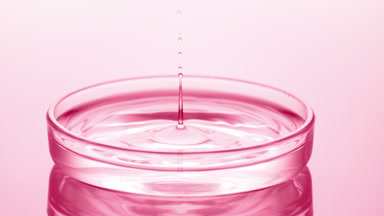 Drop of water falls into Petri dish with fluid creating ripples