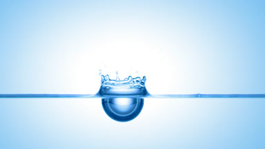 Blue drop falls down on blue liquid surface creating ripples