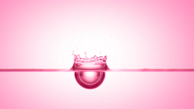Pink drop falls down on pink liquid surface creating ripples