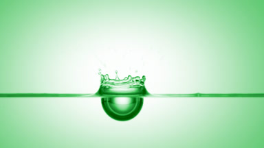 Green drop falls down on green liquid surface creating ripples