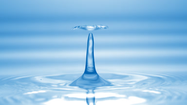 Drop of blue fluid falls down on fluid surface creating circles