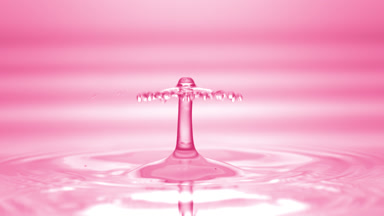 Drop of pink fluid falls down on fluid surface creating circles