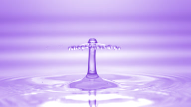Drop of violet fluid falls on fluid surface creating circles
