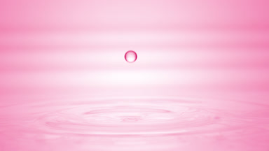 Drop of pink liquid falls on liquid surface creating circles