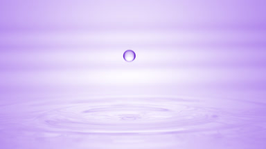 Drop of purple liquid falls on liquid surface creating circles