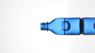 Drop falls into blue medical bottle with fluid creating splash