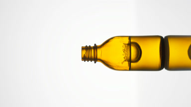 Drop falls into yellow bottle with fluid creating splash