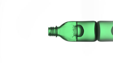 Drop falls into green medical bottle with fluid creating splash