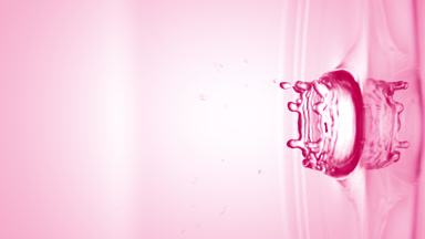 Pink drop falls down on surface of clear liquid creating circles