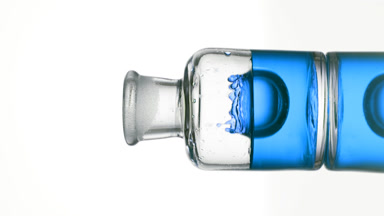 Drop of blue tansy oil is falling down into old fashioned bottle