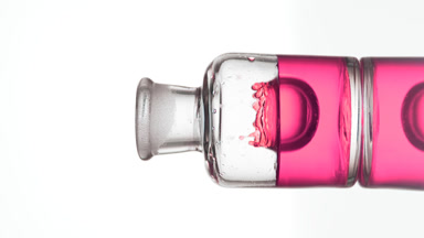 Drop of rose oil is falling down into old fashioned bottle