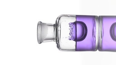 Drop of lavender oil is falling down into old fashioned bottle