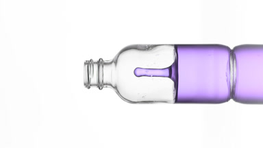 Drop of niacinamide falls into medical bottle with violet fluid