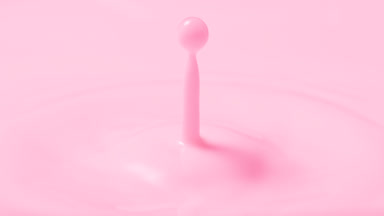 Rose milk drop falls on milk surface creating concentric circles