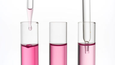 Clear fluid is dripped from dropper into one of three test tubes