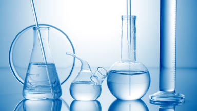 Long dropper is lowered into flask surrounded by lab glassware