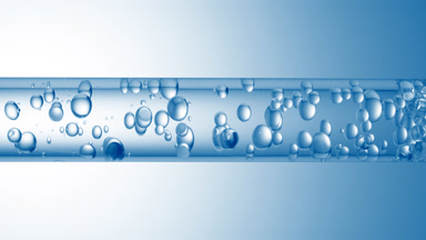 Different sized bubbles flowing in glass tube with clear liquid
