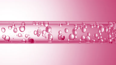 Different sized bubbles flowing in glass tube with clear liquid