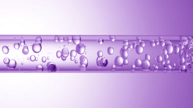 Different sized bubbles flowing in glass tube with clear liquid