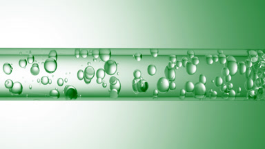 Different sized bubbles flowing in glass tube with clear liquid