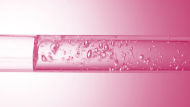 Transparent liquid flows in glass tube creating bubbles