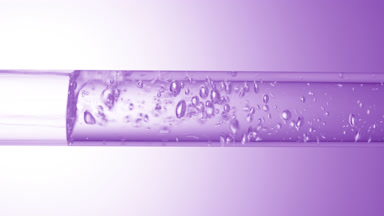 Transparent liquid flows in glass tube creating bubbles